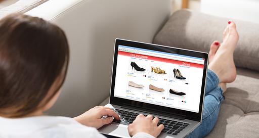 Donna seduta sul divano con laptop appoggiato sulle gambe. Sullo schermo si vede il suo e-commerce personalizzato. 